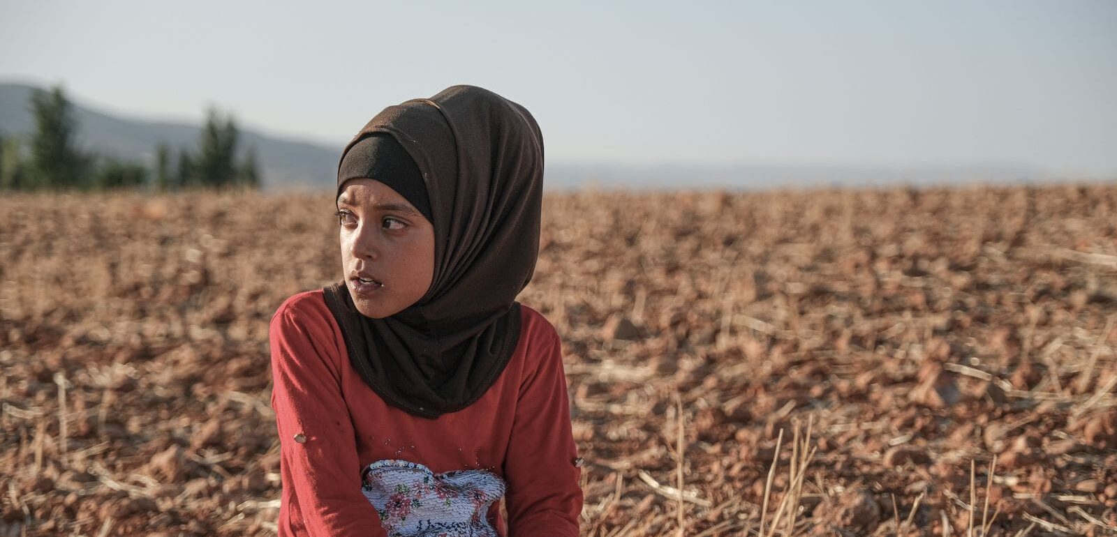 Young Syrian refugee girl resting in a potato field after working, from 'Edge of the Valley' documentary.